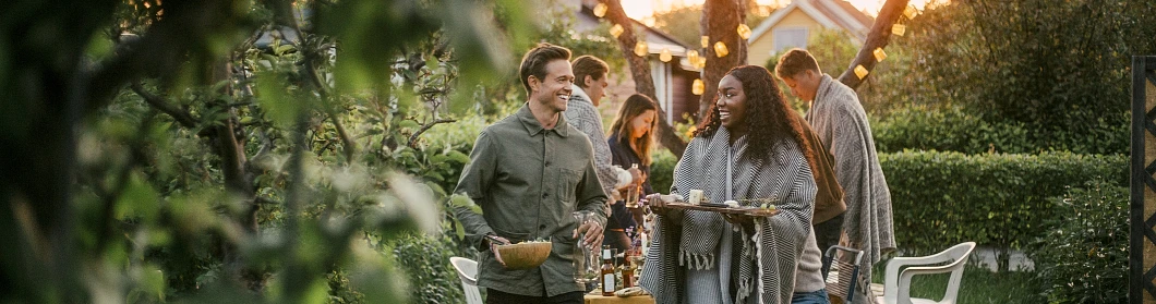 Smiling male and female talking in yard during dinner party Smiling male and female talking in yard during dinner party